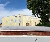House under construction with light blue foam walls and wooden roof frame on a hillside.