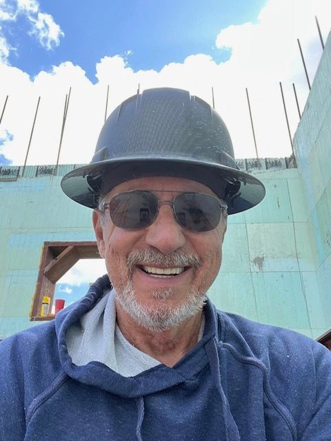 Construction site: Insulated concrete form walls being built; workers, bracing, and support structures visible.