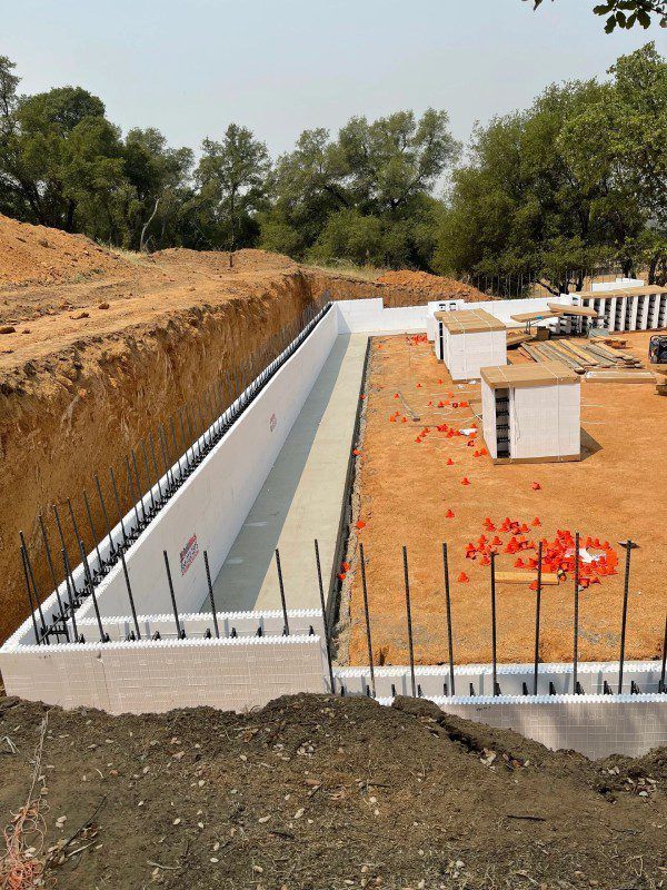 Reinforced steel grid (rebar) in a construction site, set in a rectangular formation against a dirt wall.