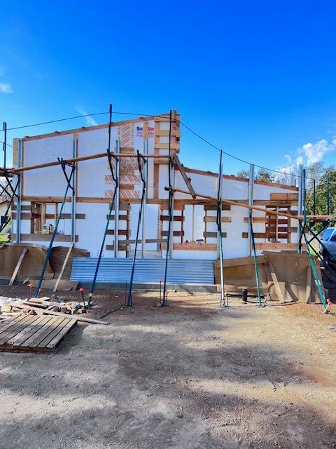 Construction of a building with white foam blocks and wooden frames under a blue sky.