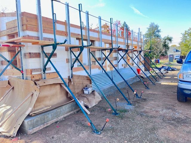 Construction site with ICF walls, supported by adjustable braces and scaffolding; exterior shot.