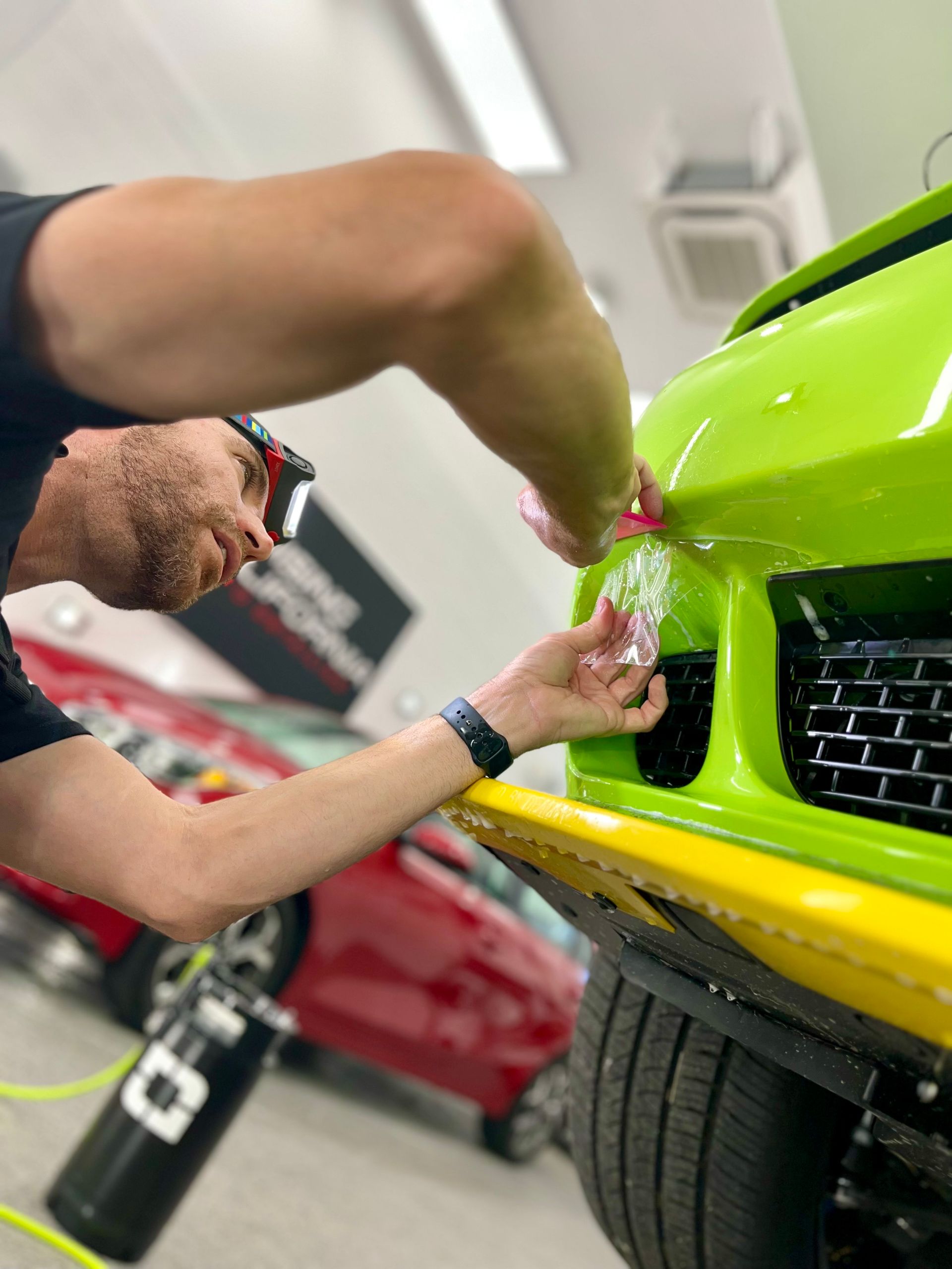 A man is working on a green car in a garage.