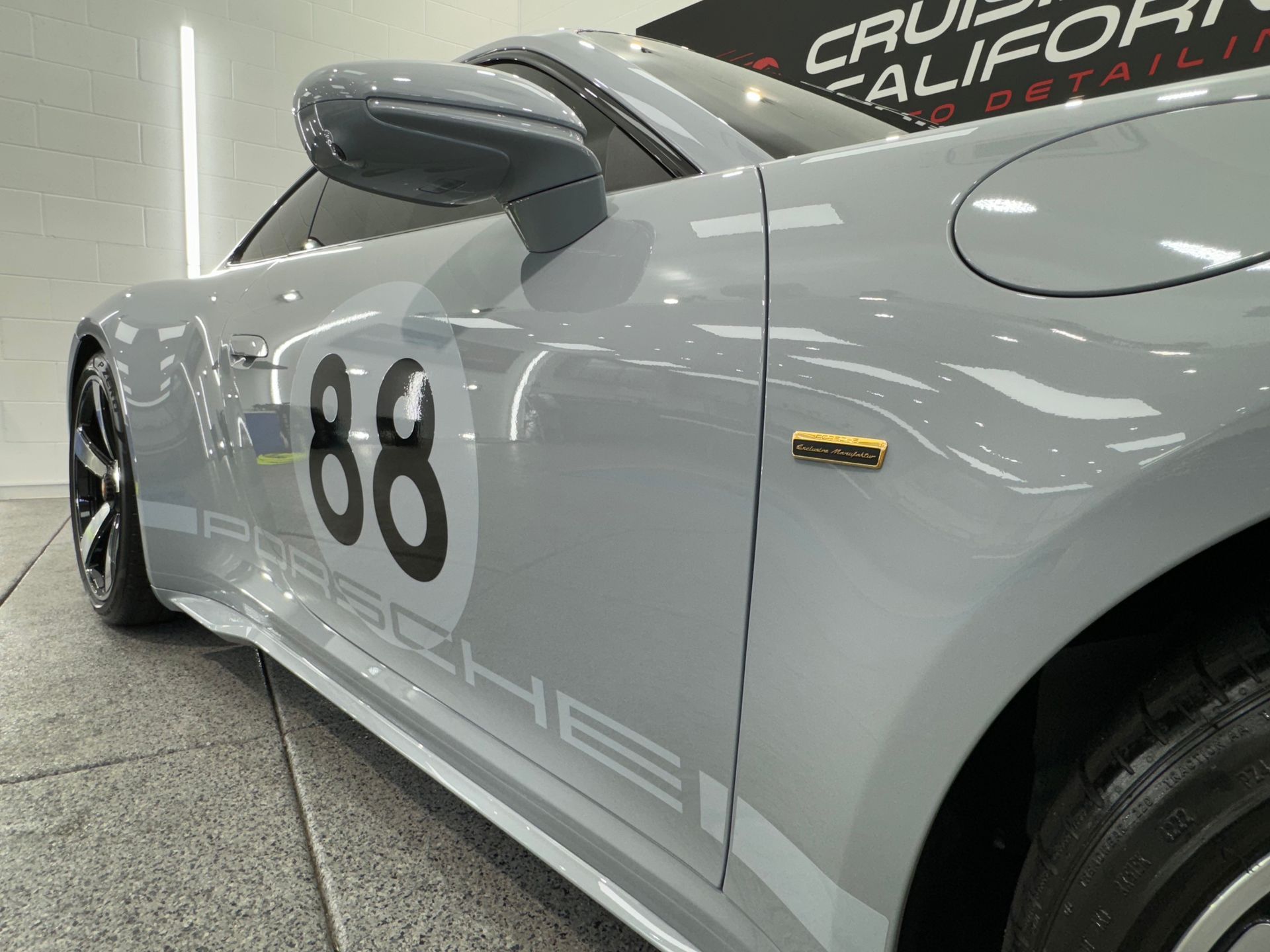 A grey porsche with the number 88 on the side is parked in a garage.