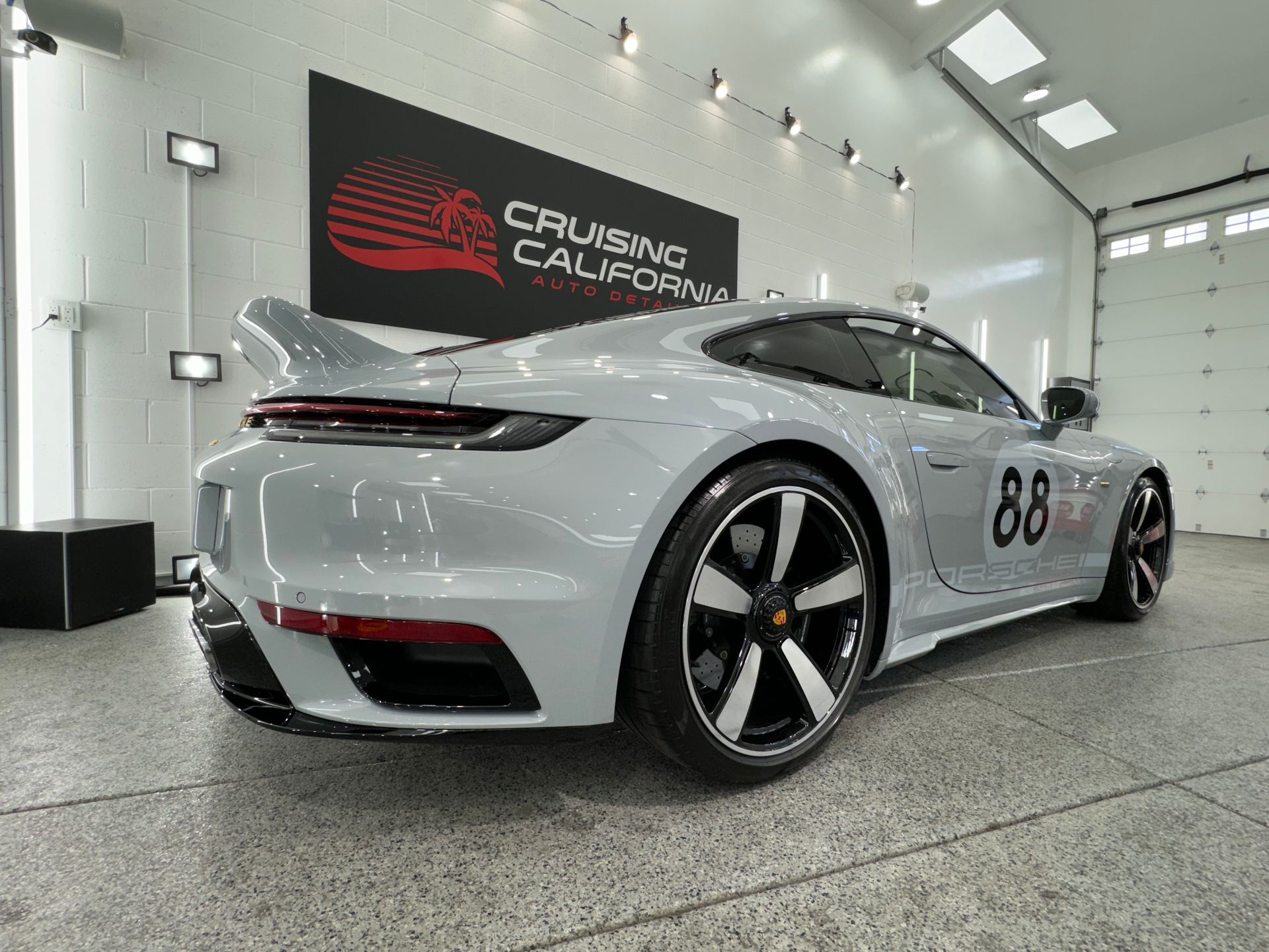 A white porsche 911 is parked in a garage.