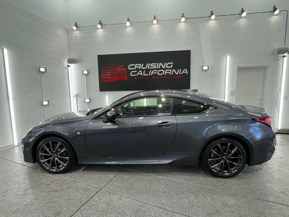 A gray sports car is parked in a room with a sign that says cruising california.