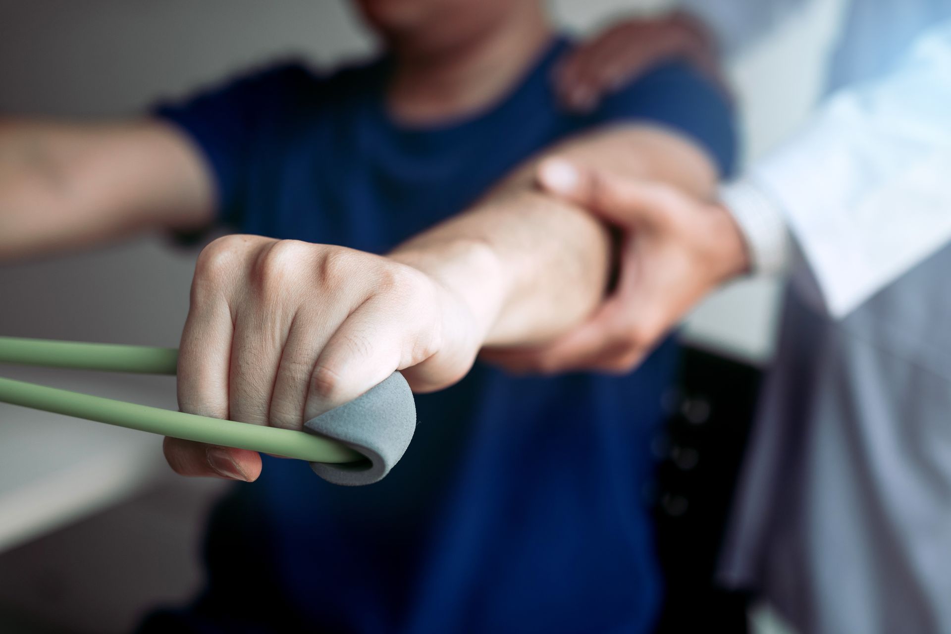 A physical therapist is guiding a patient with a band stretch in a clinic.
