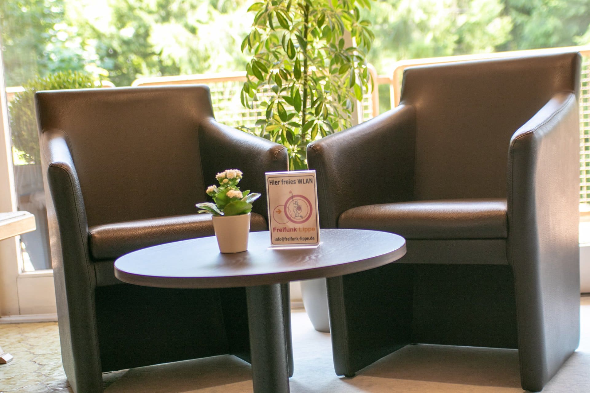 Neben einem Tisch stehen zwei Stühle, auf denen eine Uhr steht.