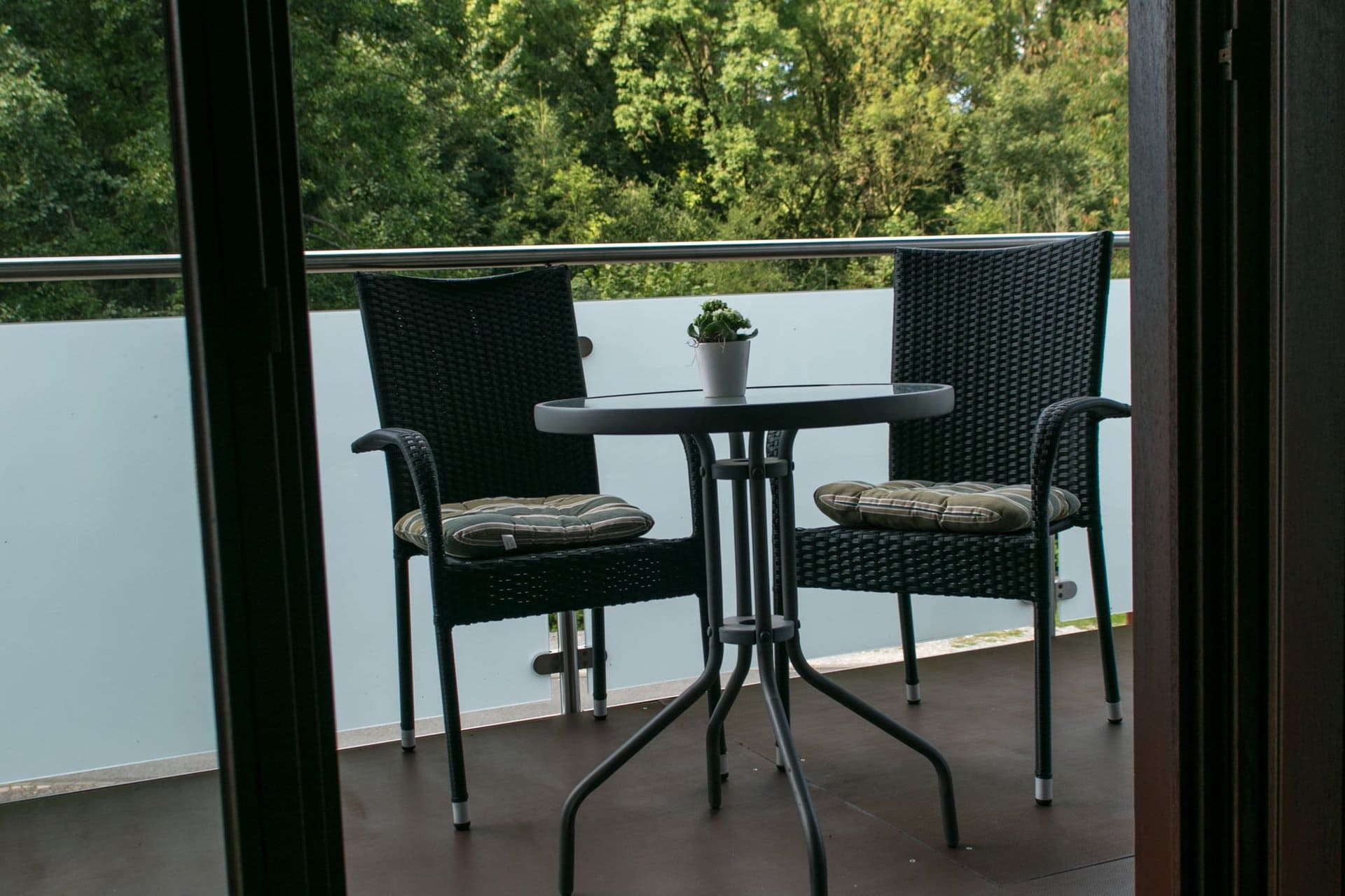 Ein Tisch und Stühle auf einem Balkon mit Bäumen im Hintergrund