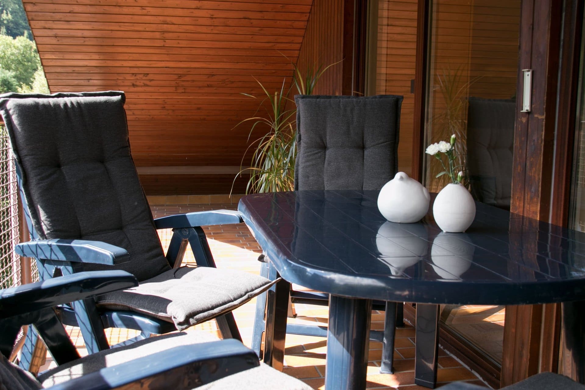 Ein Tisch und Stühle auf einem Balkon mit zwei Vasen darauf