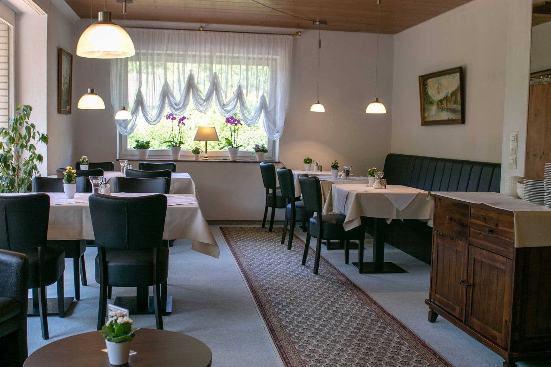 Ein Esszimmer mit Tischen und Stühlen und einem Fenster