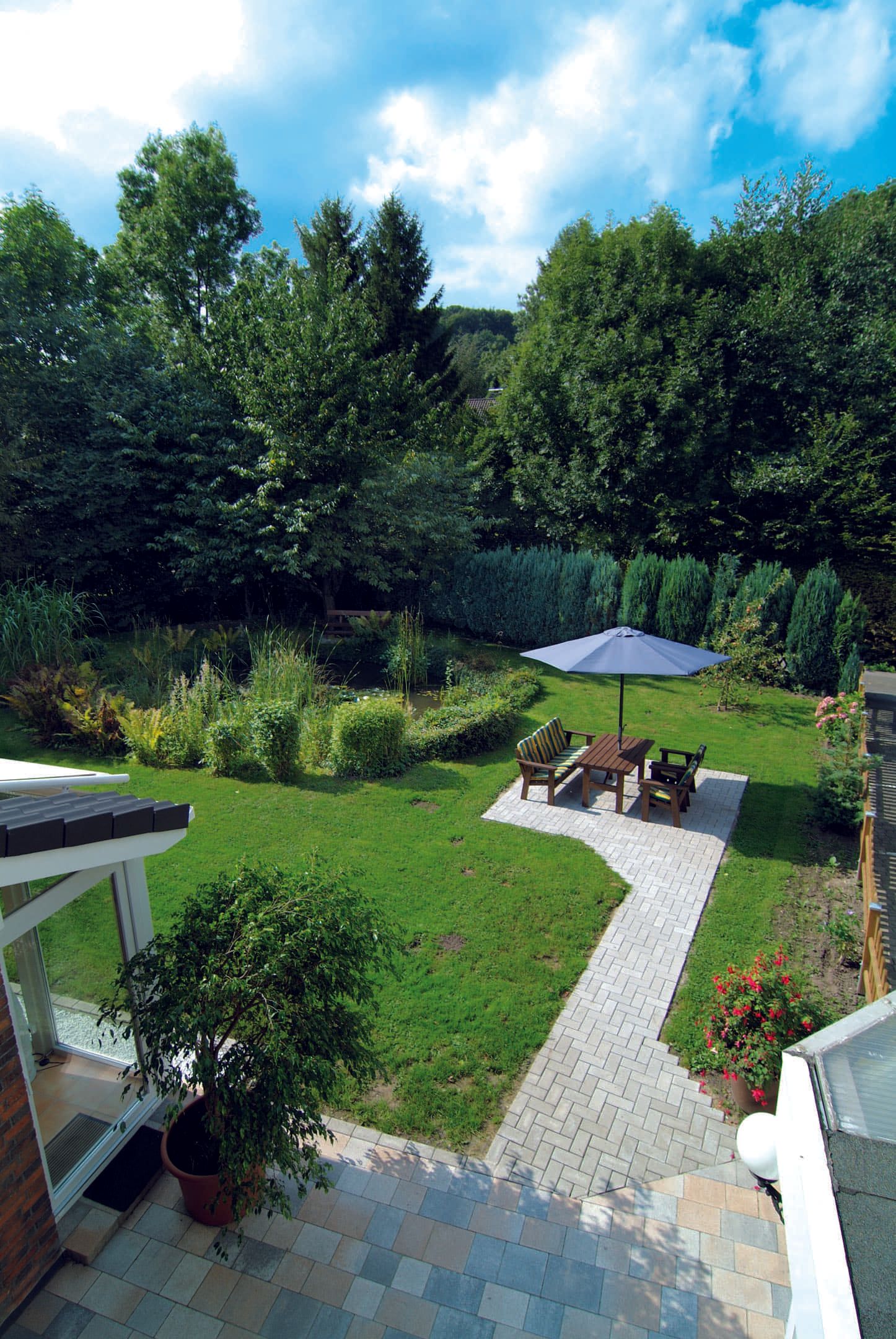 Eine Luftaufnahme eines Gartens mit einem Tisch und Stühlen unter einem Sonnenschirm.