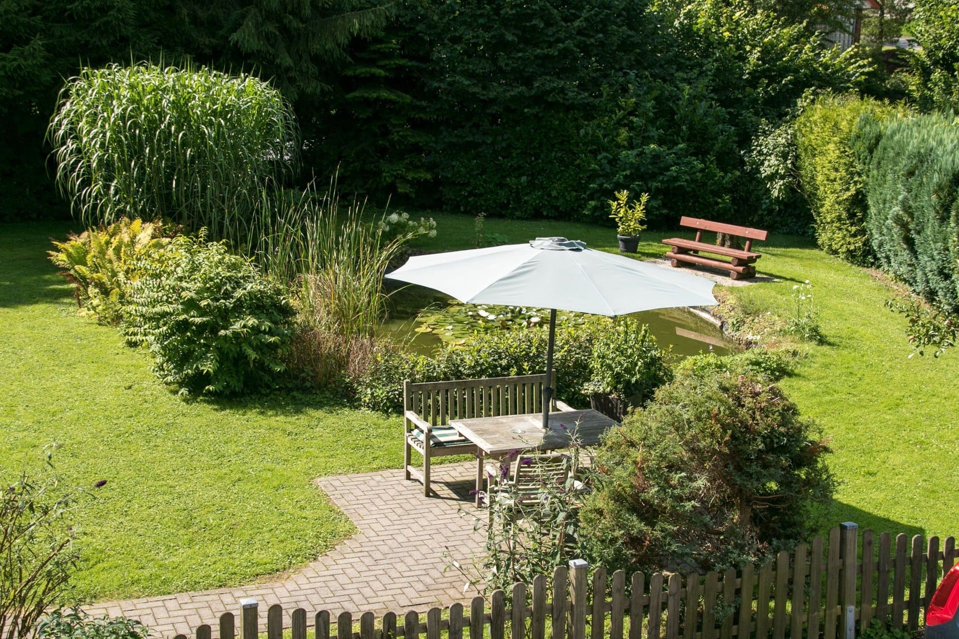 Ein Garten mit Tisch und Stühlen unter einem Sonnenschirm