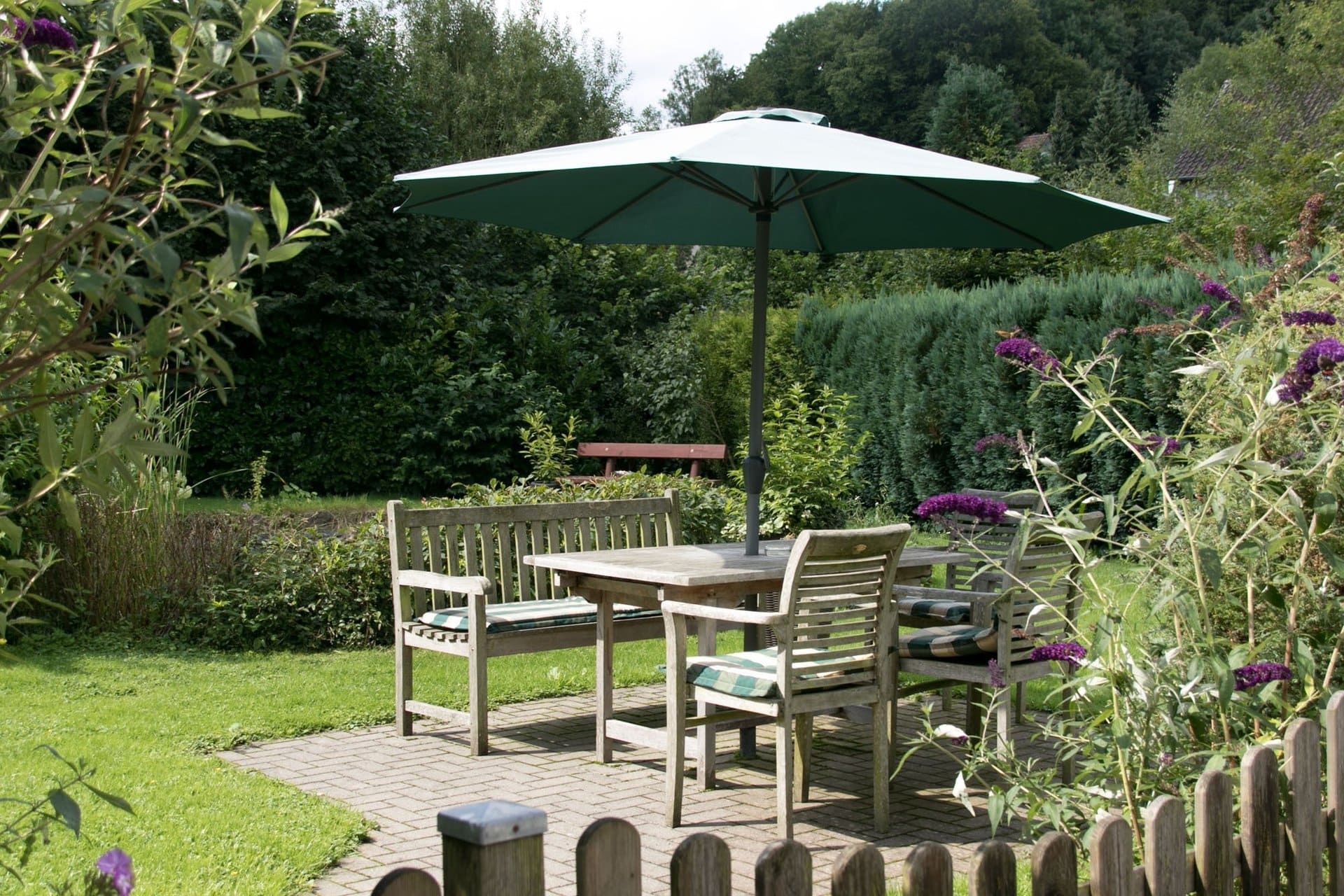 Ein Tisch und Stühle unter einem Sonnenschirm in einem Garten