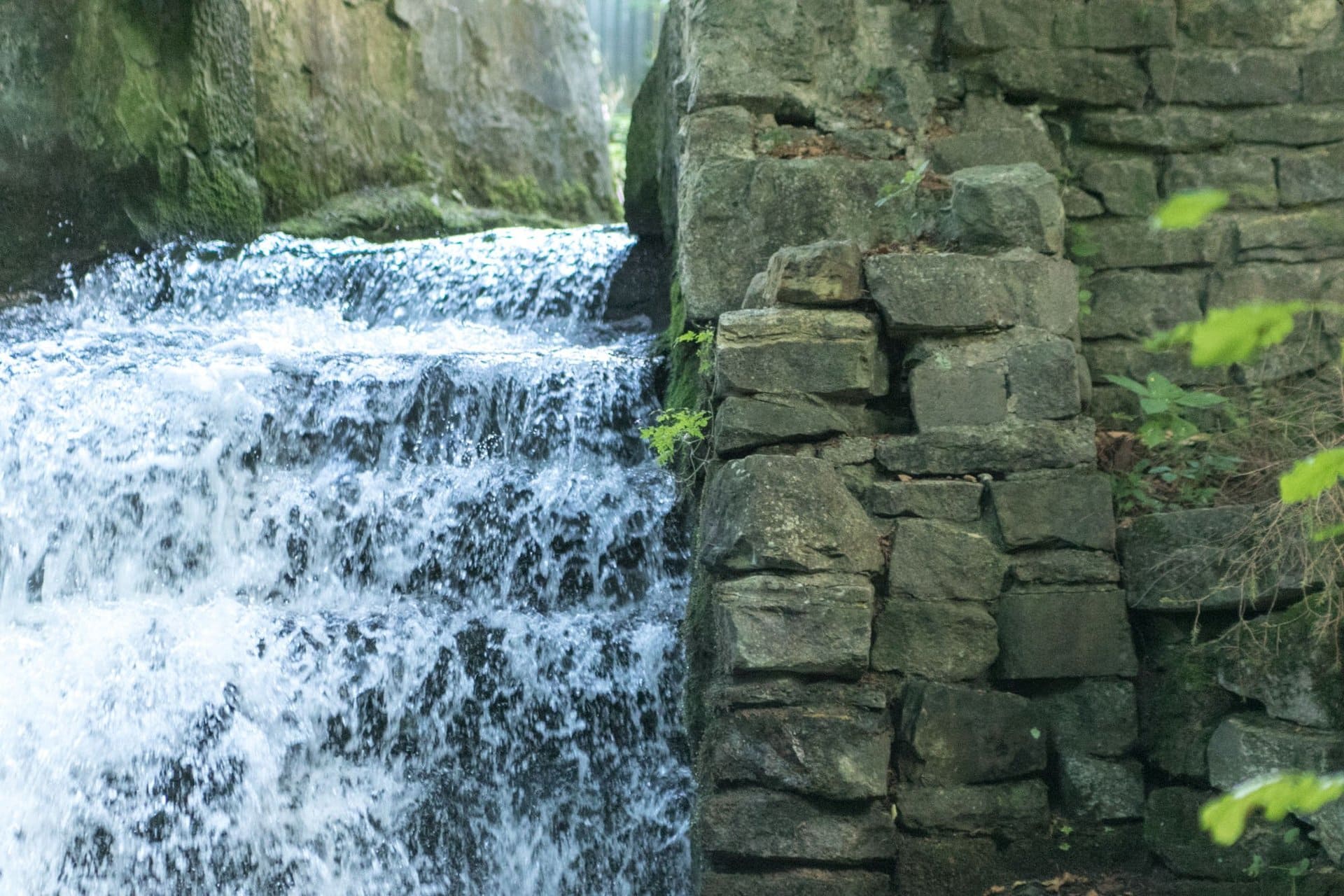 Ein Wasserfall ist von einer Steinmauer und Bäumen umgeben.
