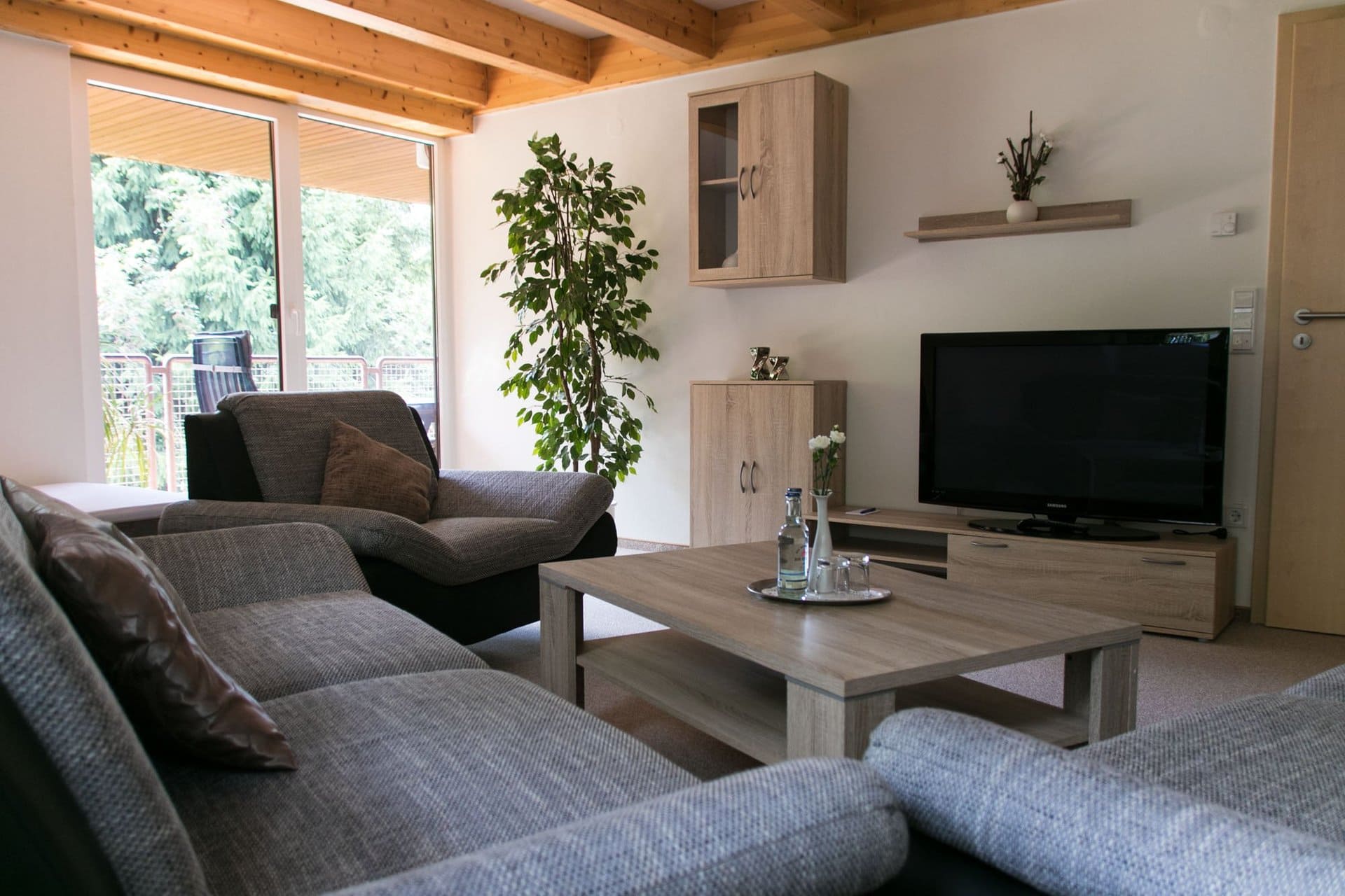 Ein Wohnzimmer mit Couch, Sessel, Couchtisch und Fernseher.