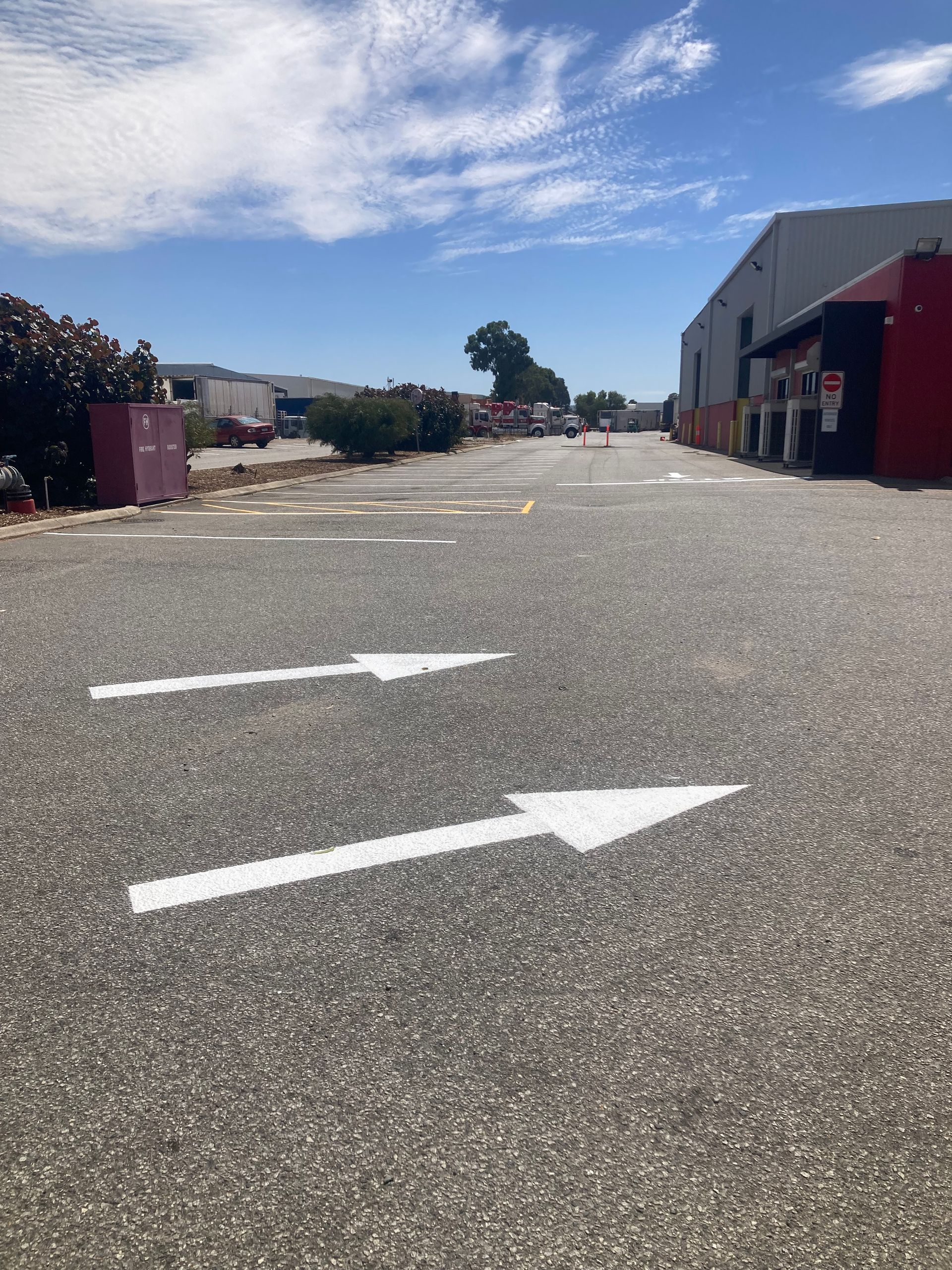 Asphalt parking area with white directional arrows under a blue sky.