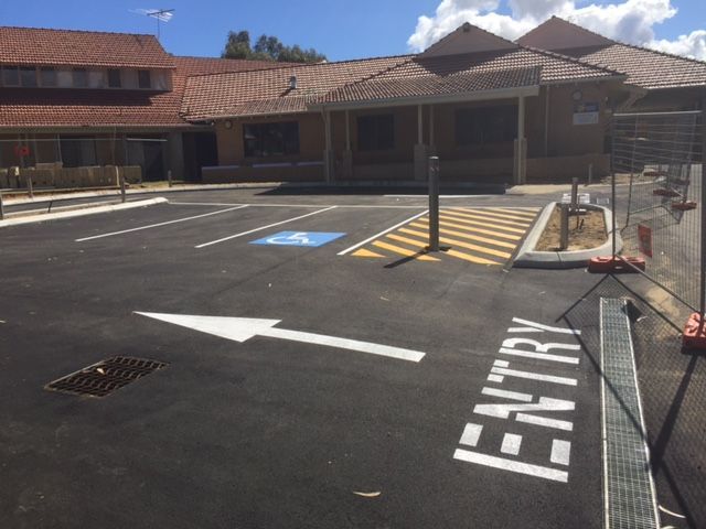 Asphalt parking lot with disabled parking, entry sign and ramp to the building.