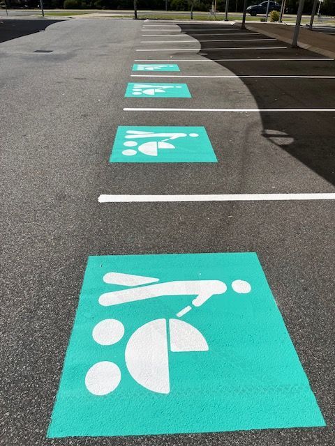 Parking spaces painted with green squares featuring white symbols for parents with strollers.