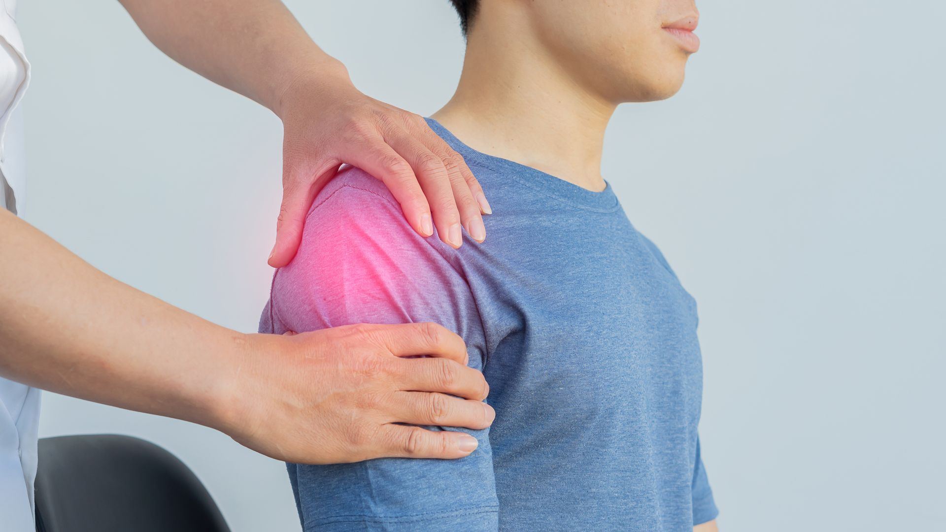 A person's shoulder is examined by a medical professional. 