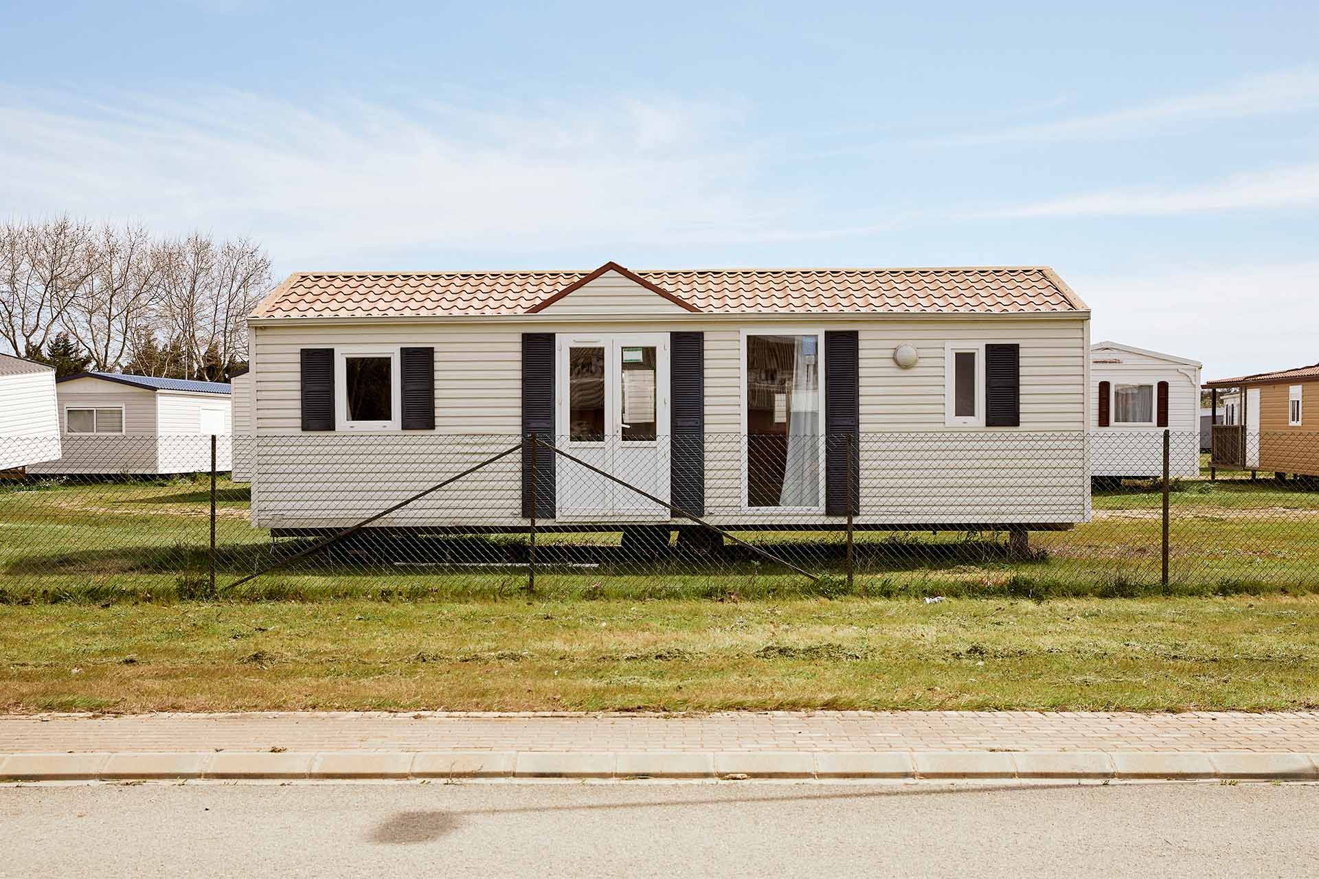 Single wide manufactured home with fenced yard, windows, and front door.
