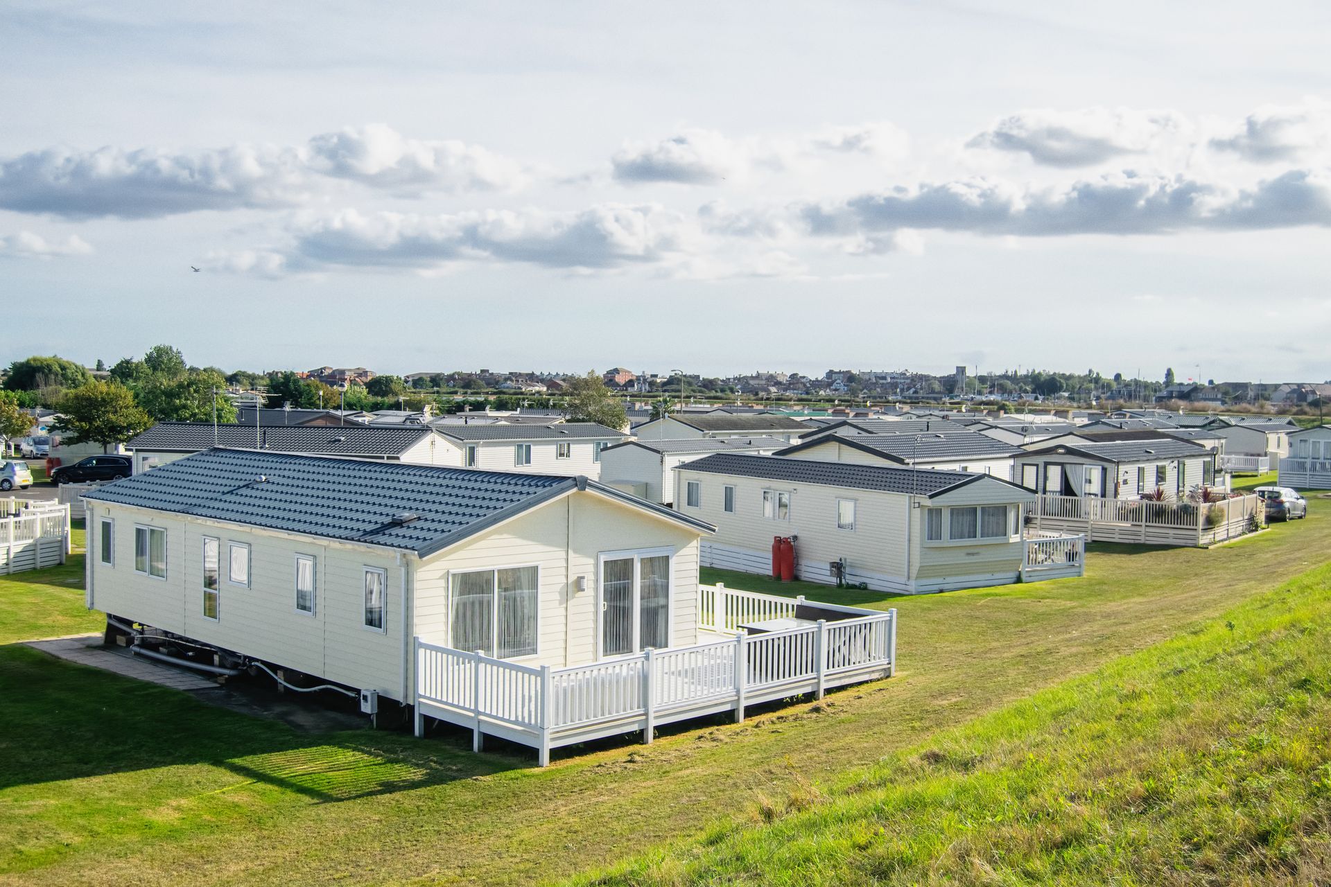 Row of modern mobile homes set on a grassy hillside in a large residential park.