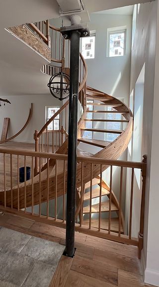 A wooden spiral staircase with a wooden railing in a house.
