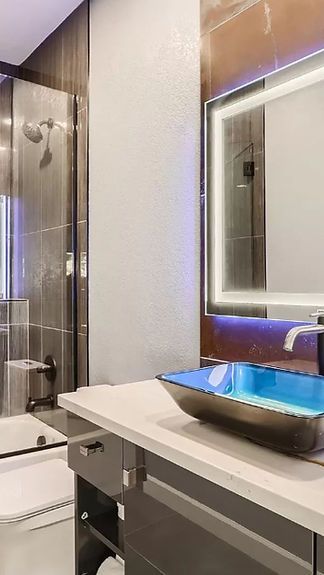 A bathroom with a sink , toilet , shower and mirror.