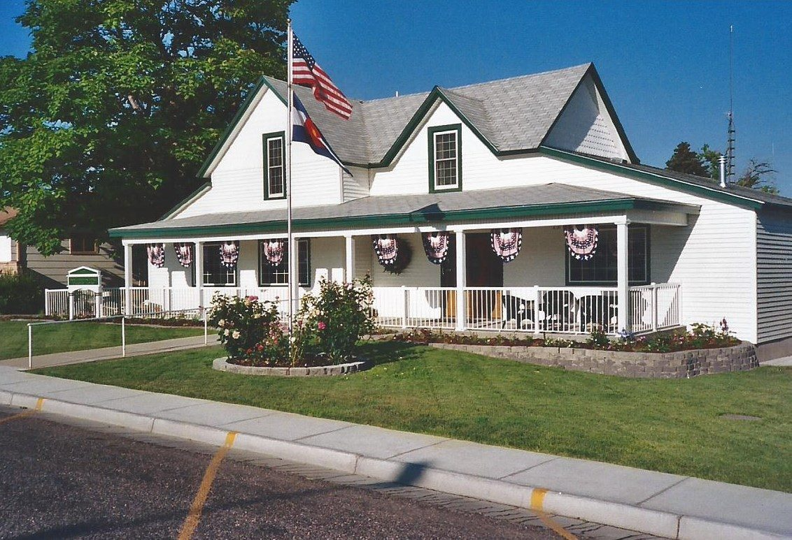 White house with American flag, front porch, and wreaths.