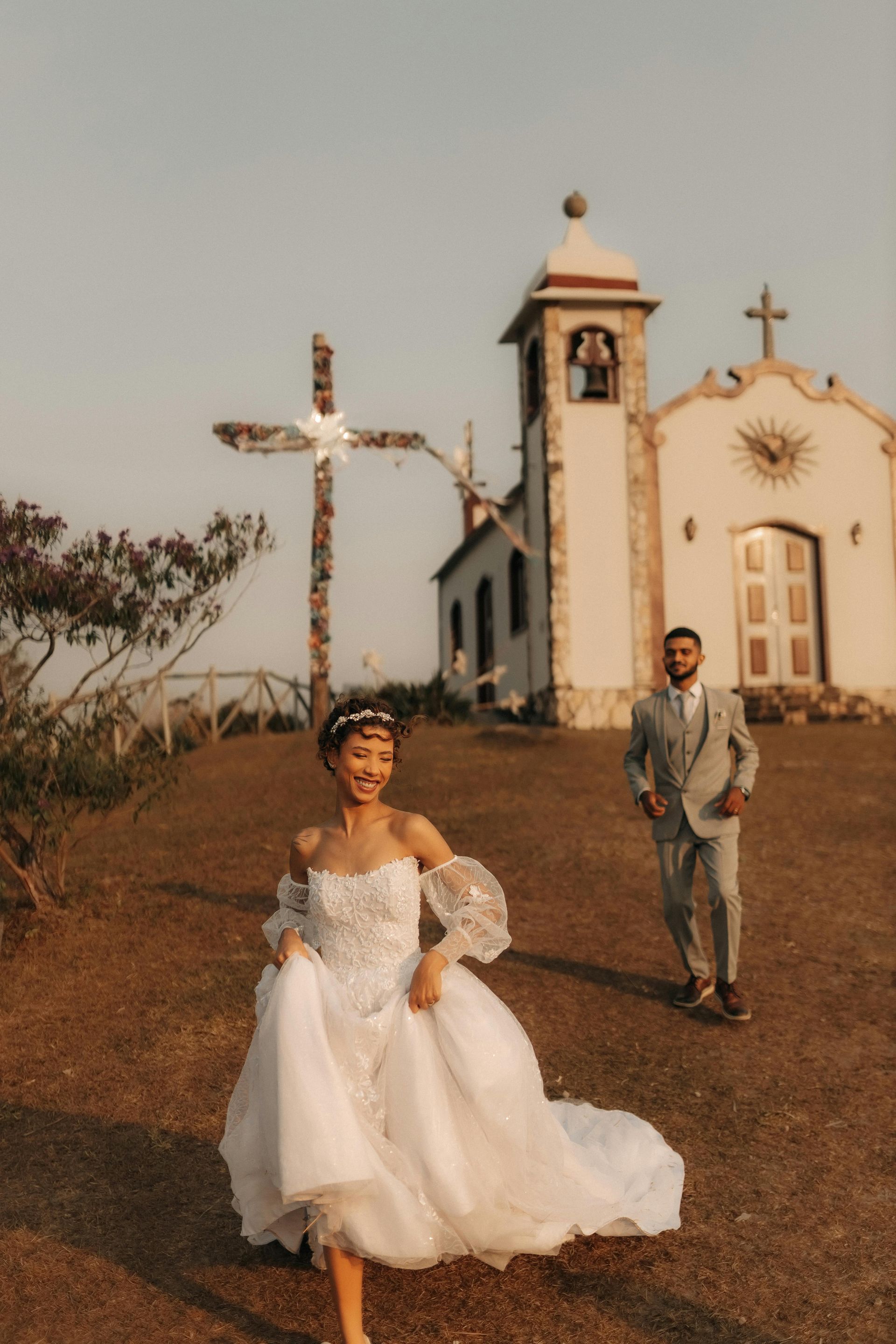 A bride and groom are running in front of a church.