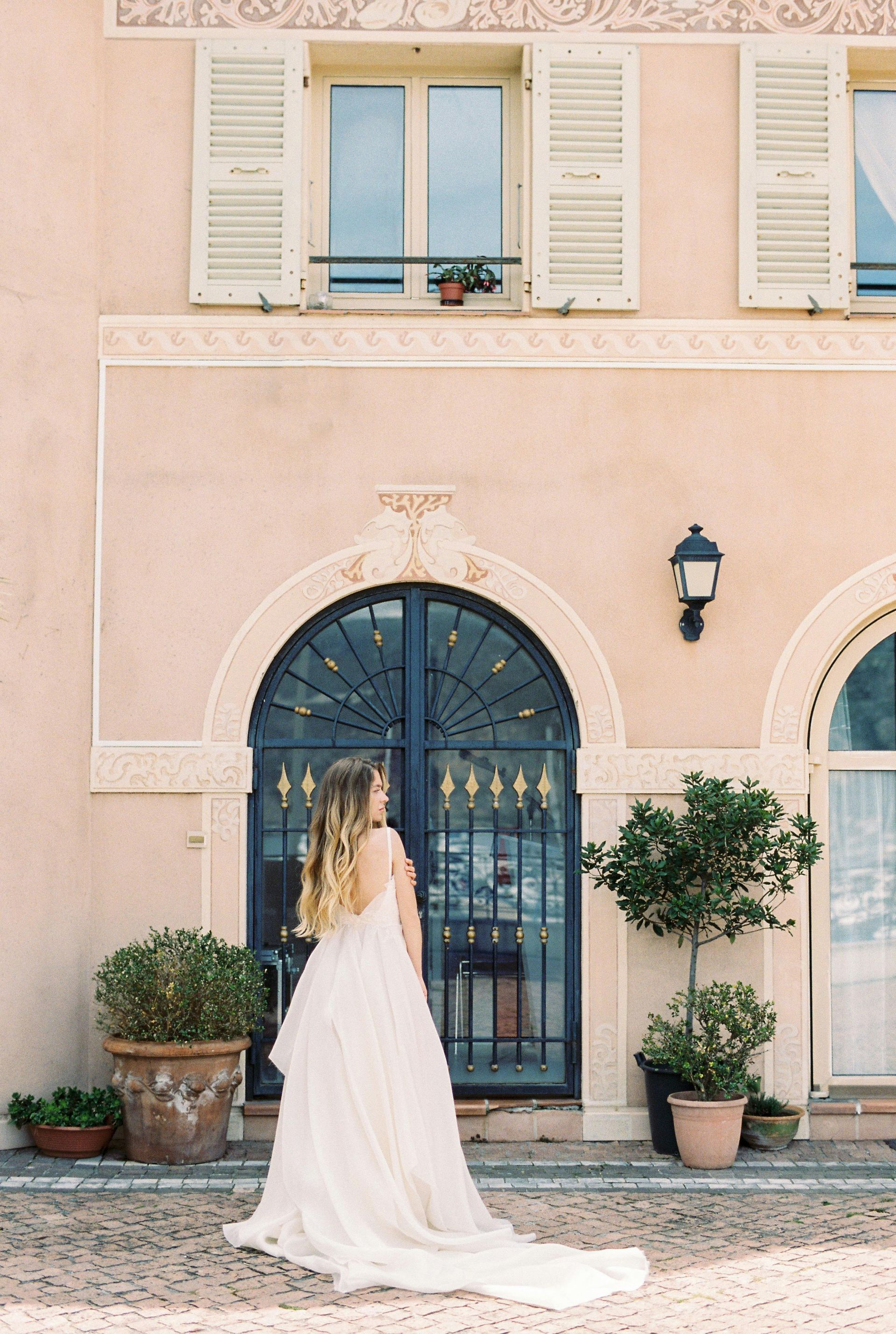 A woman in a wedding dress is standing in front of a building.