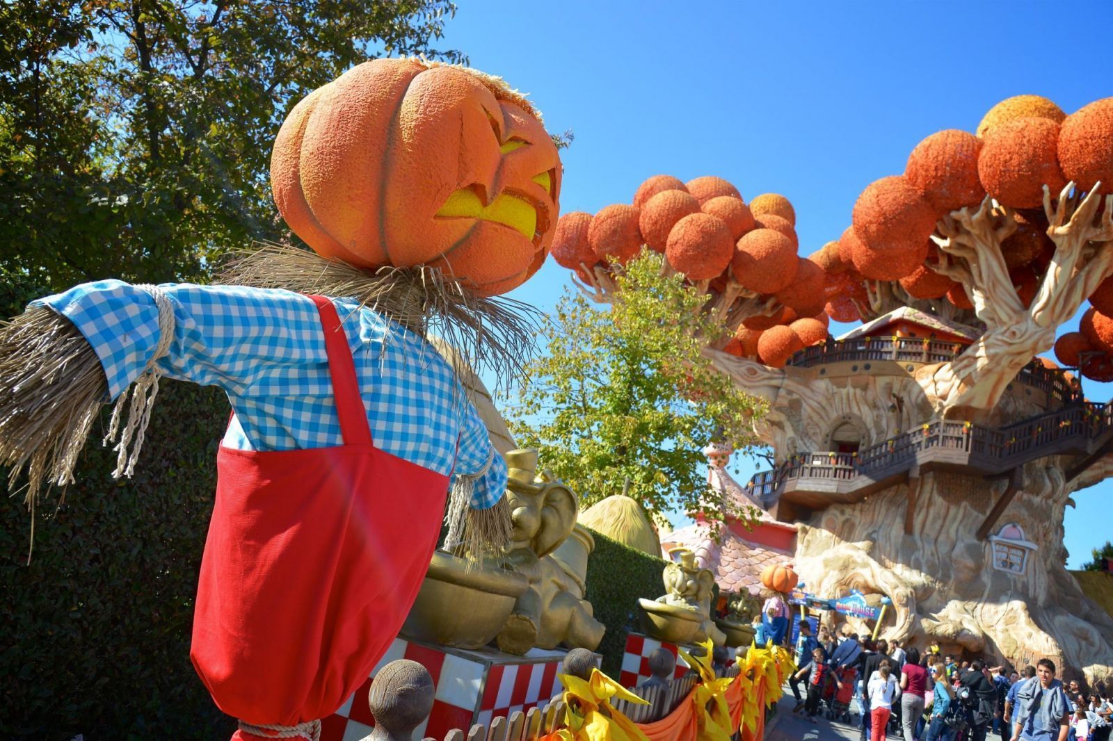 Decorazione a forma di spaventapasseri con la testa di zucca in una soleggiata festa all'aperto con colorate decorazioni autunnali