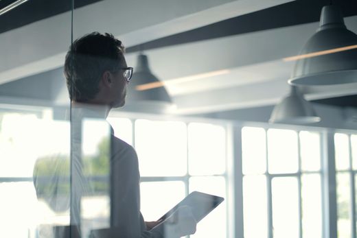 A man is standing in front of a glass wall holding a clipboard.