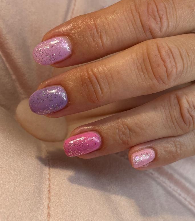 Een close-up van de roze en paarse fibergel nagels van een vrouw