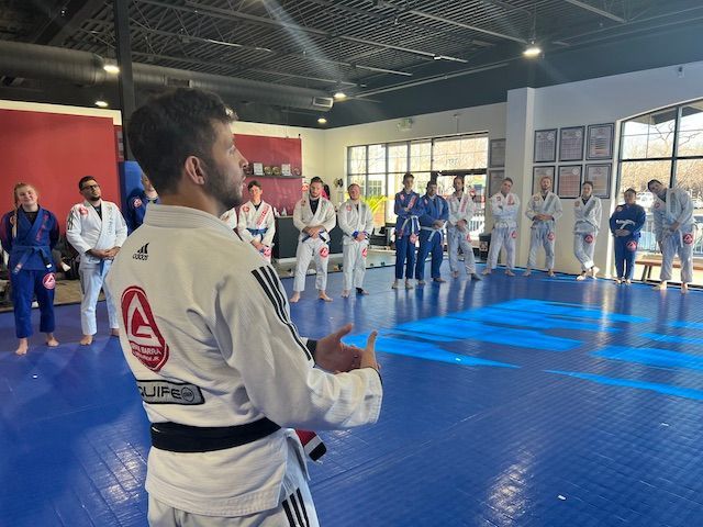 A man is standing in front of a group of people in a gym.