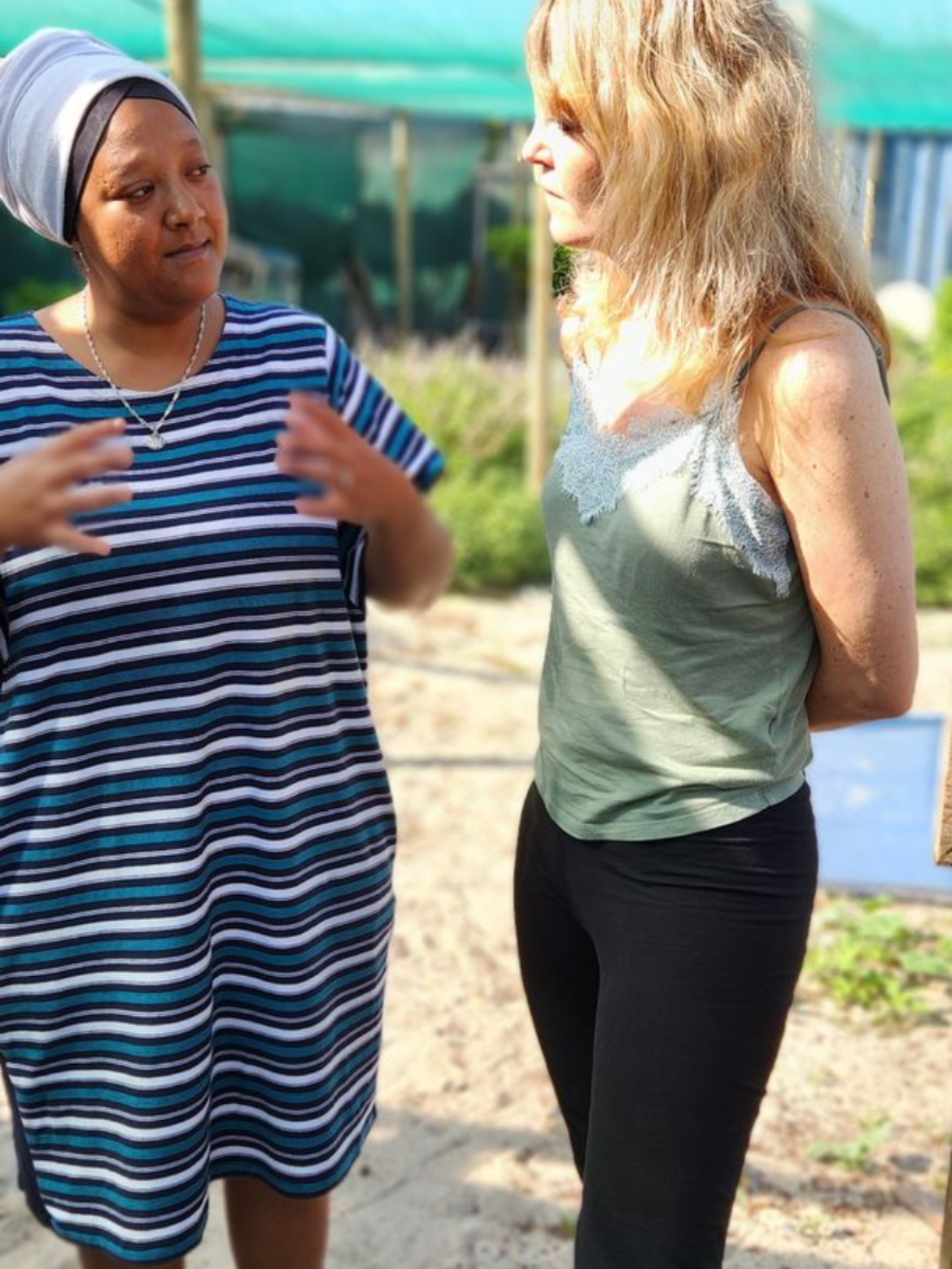A woman is talking to a group of children sitting on the ground.