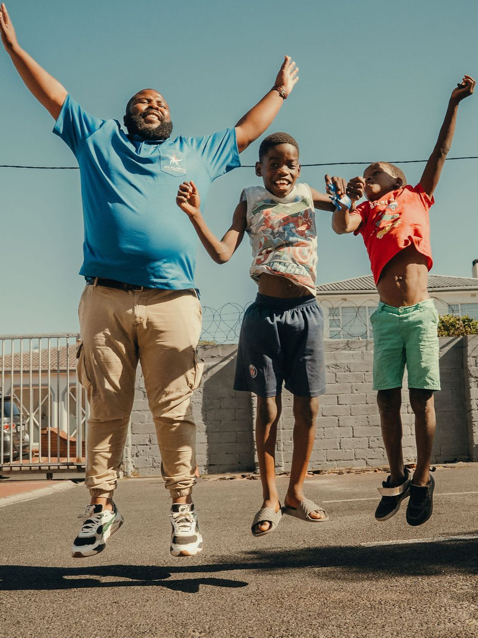 A woman is talking to a group of children sitting on the ground.