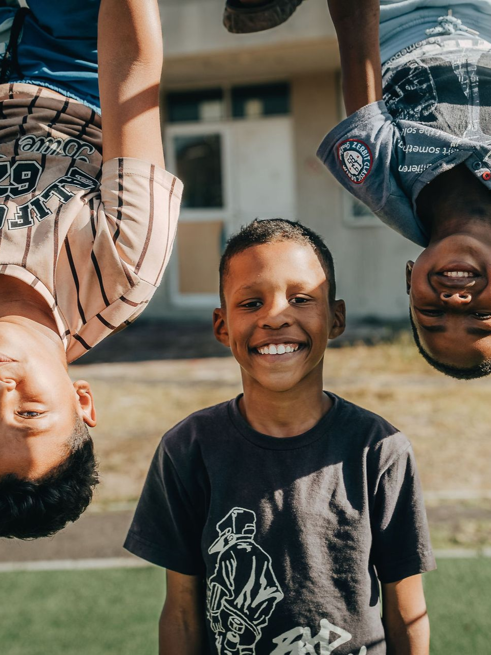 A woman is talking to a group of children sitting on the ground.