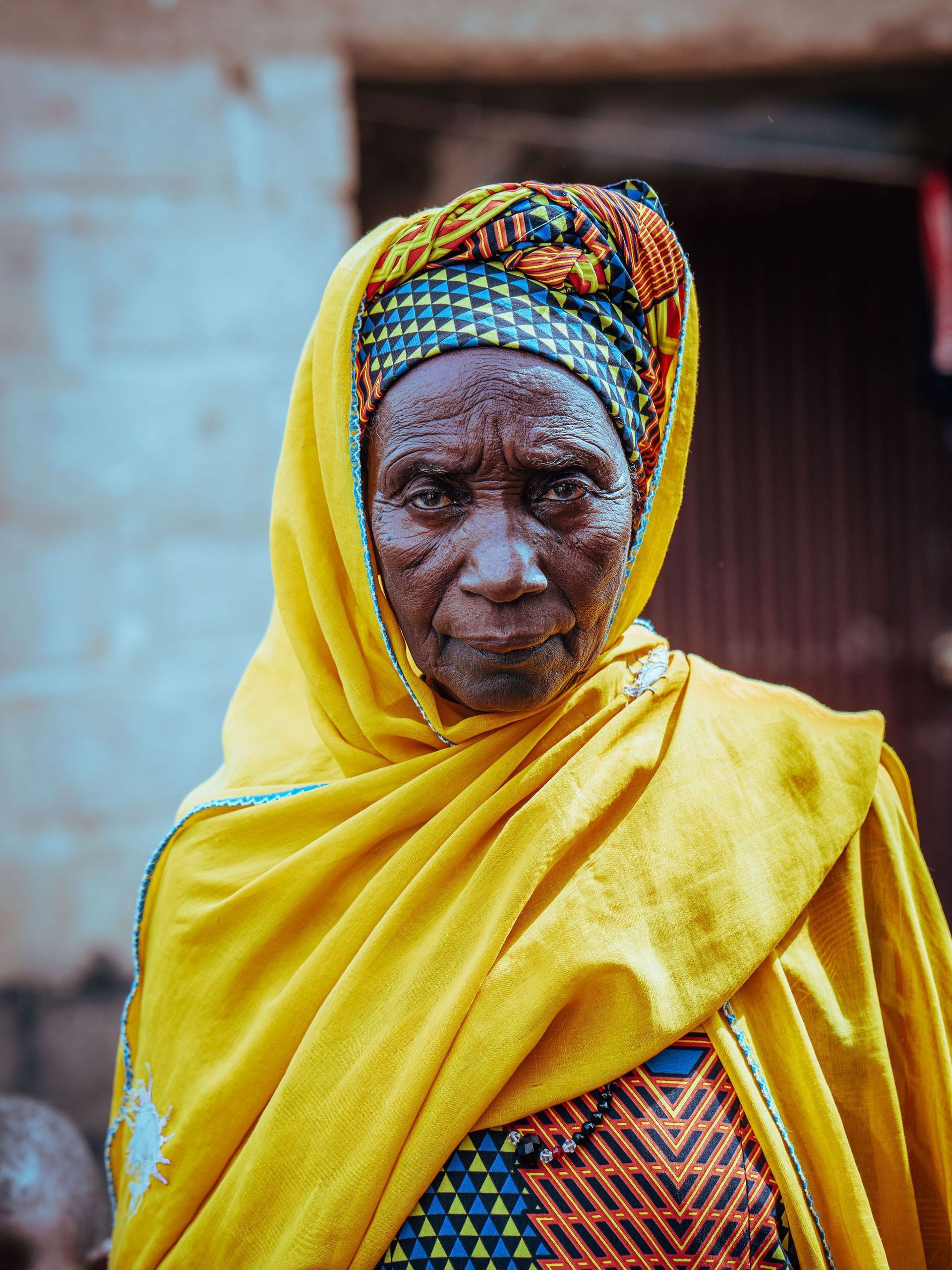 An older woman wearing a yellow scarf around her head.