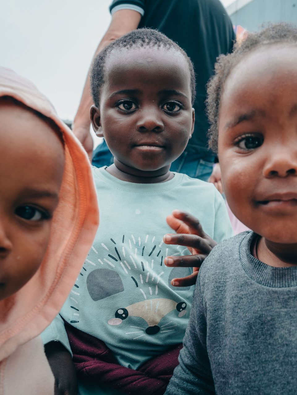 Three young children are sitting next to each other and looking at the camera.