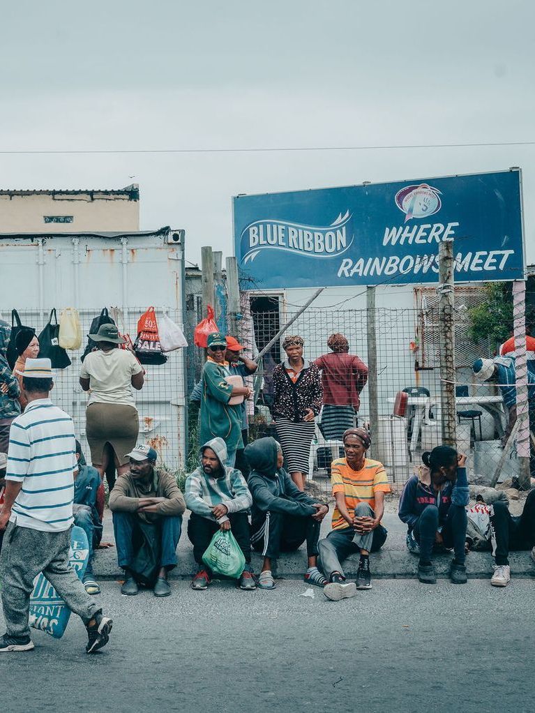 A little girl in a white dress is standing in the dirt.