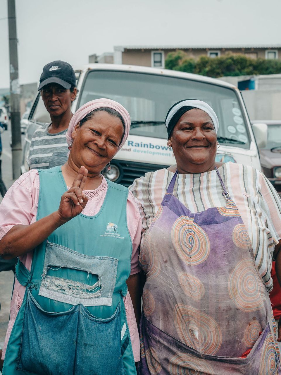 Two women are posing for a picture in front of a truck.
