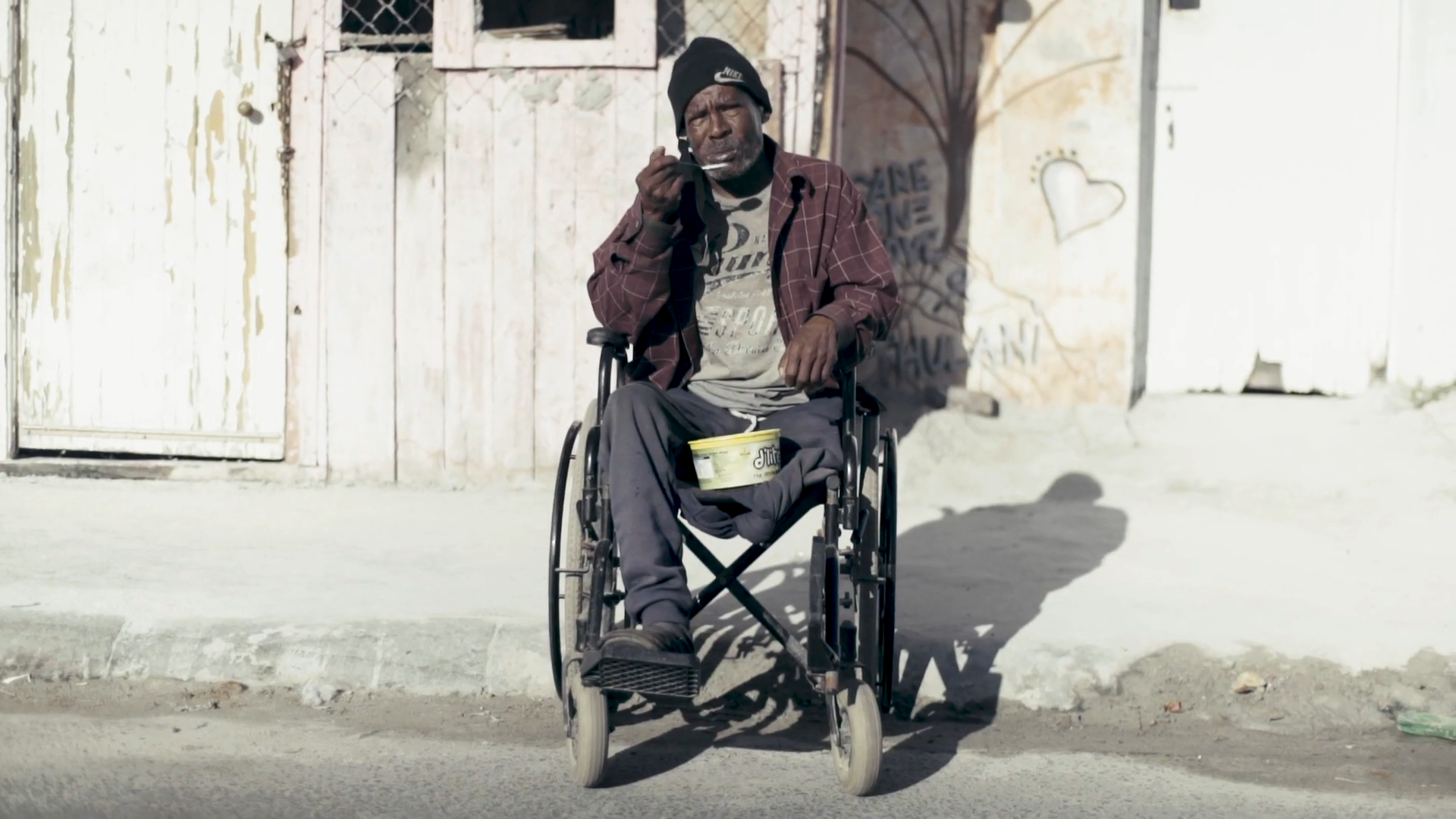 A man in a wheelchair is talking on a cell phone.