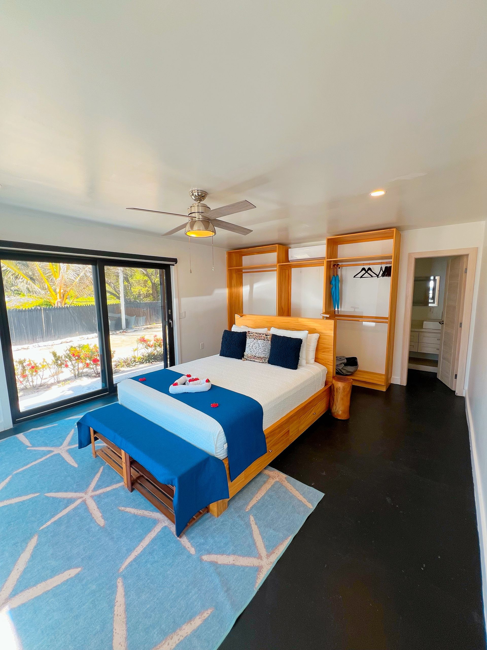 Bedroom with a bed, blue rug, sliding door, and wooden closet.