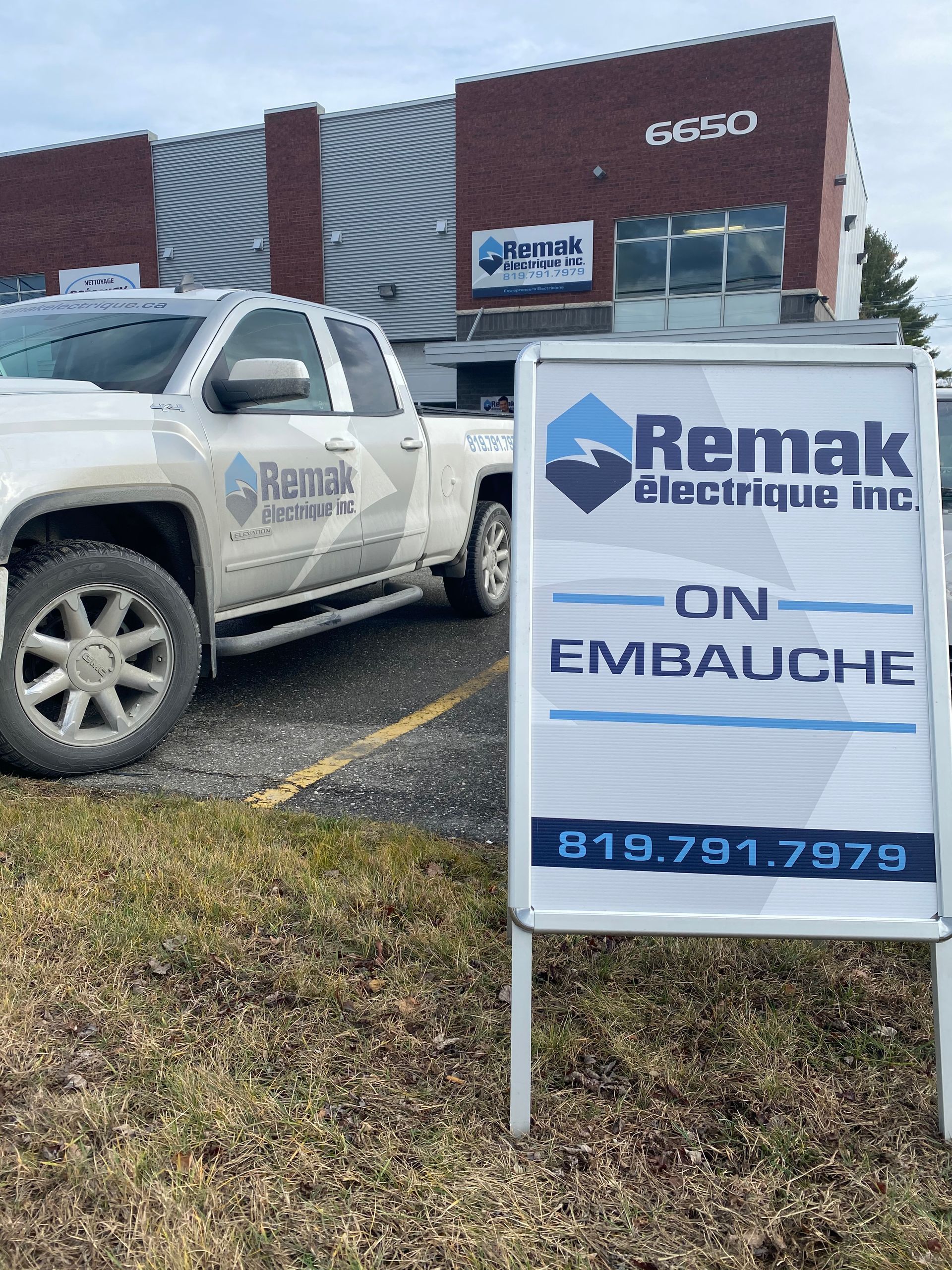 Un camion est garé devant un bâtiment à côté d'un panneau.