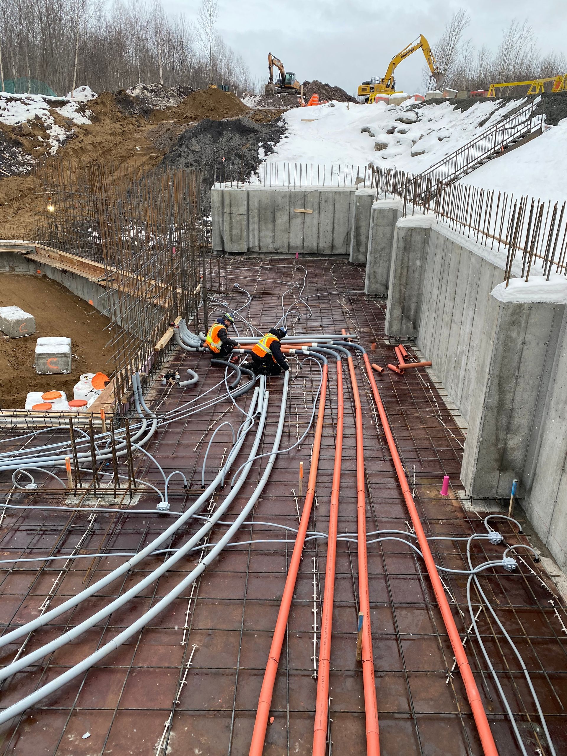 Un tas de tuyaux oranges sont posés sur le sol d'un chantier de construction.