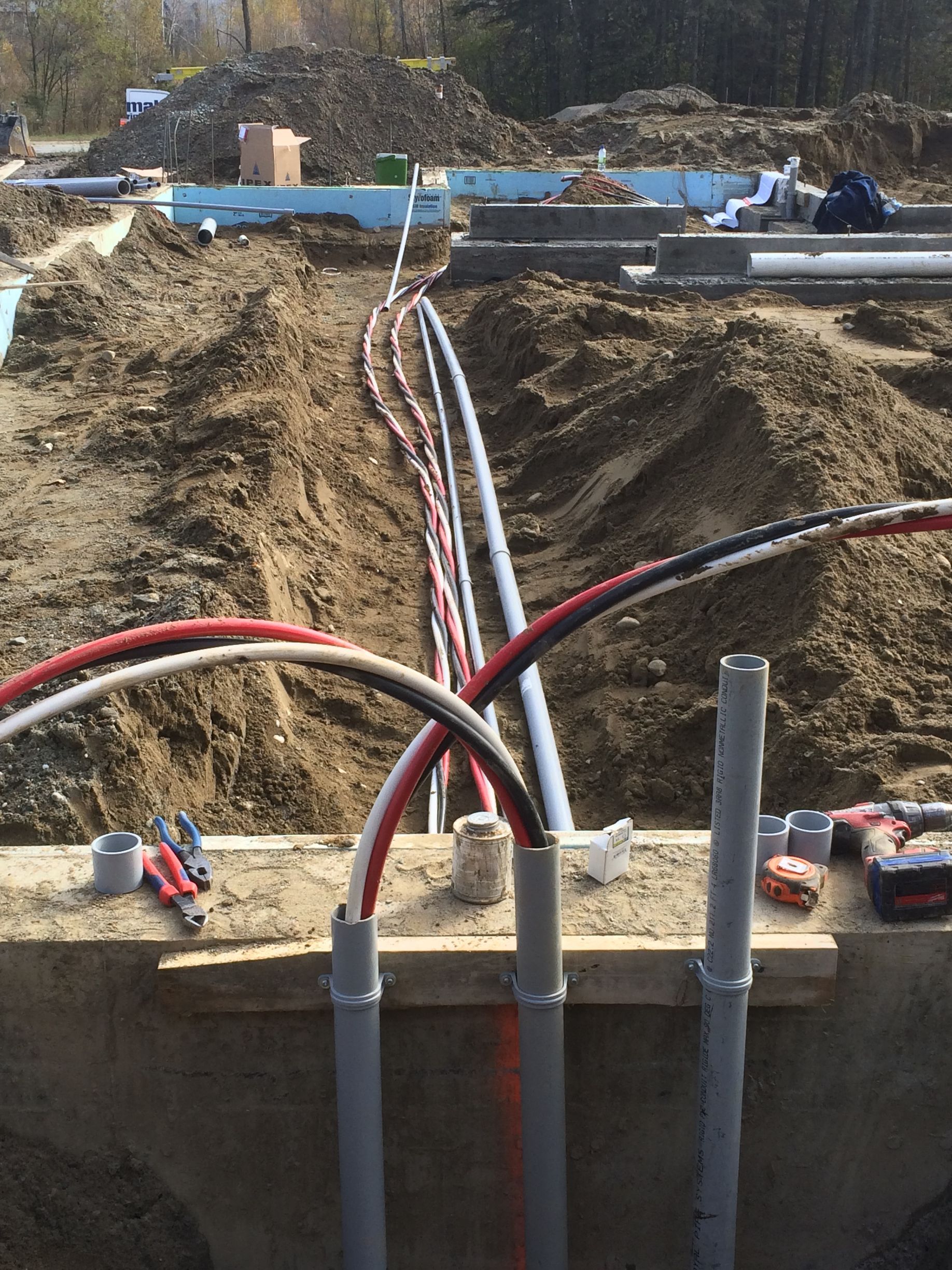Un tas de fils électriques traînent dans la terre sur un chantier de construction.