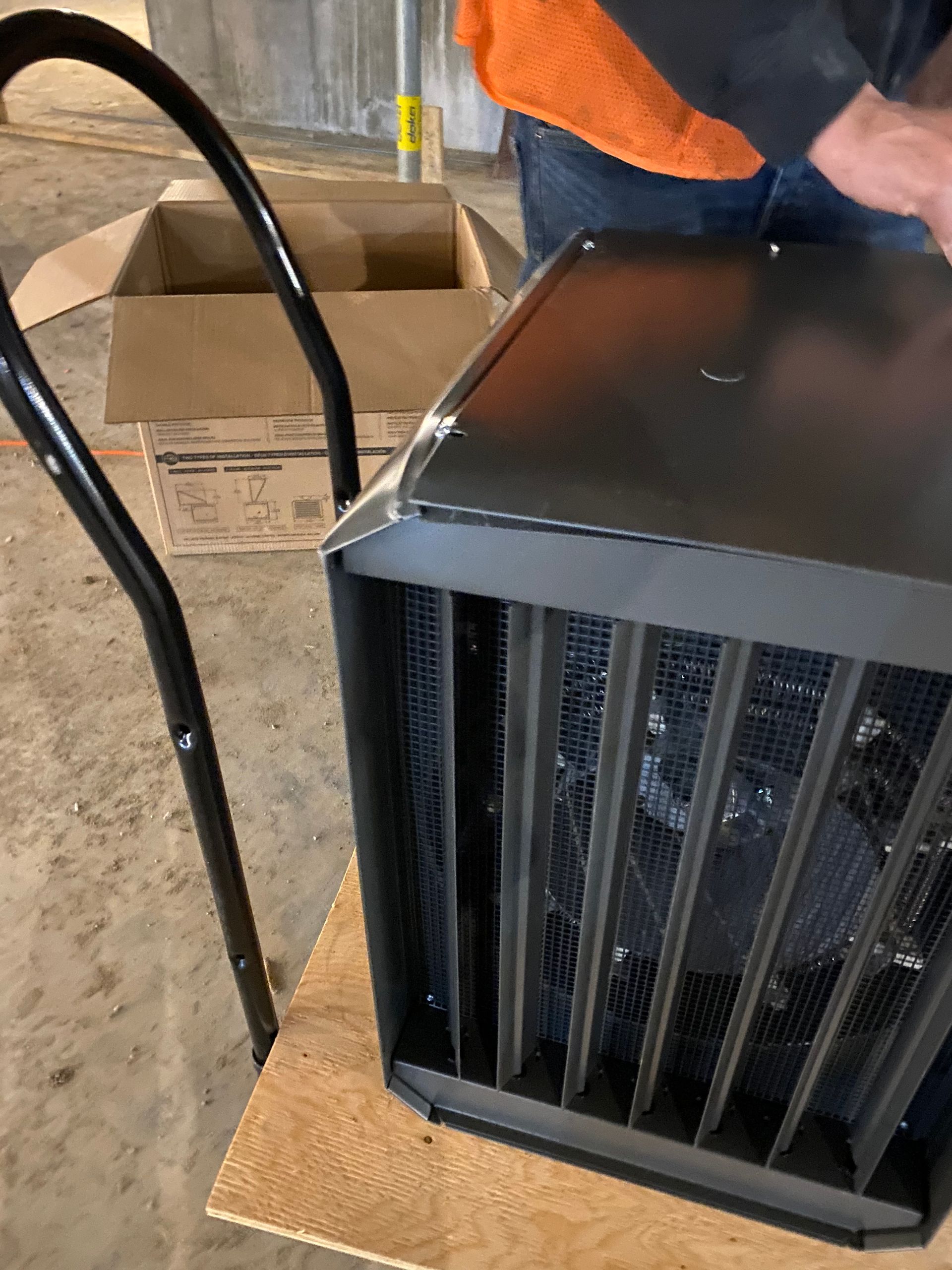 Un homme se tient debout à côté d'un radiateur sur une table en bois.