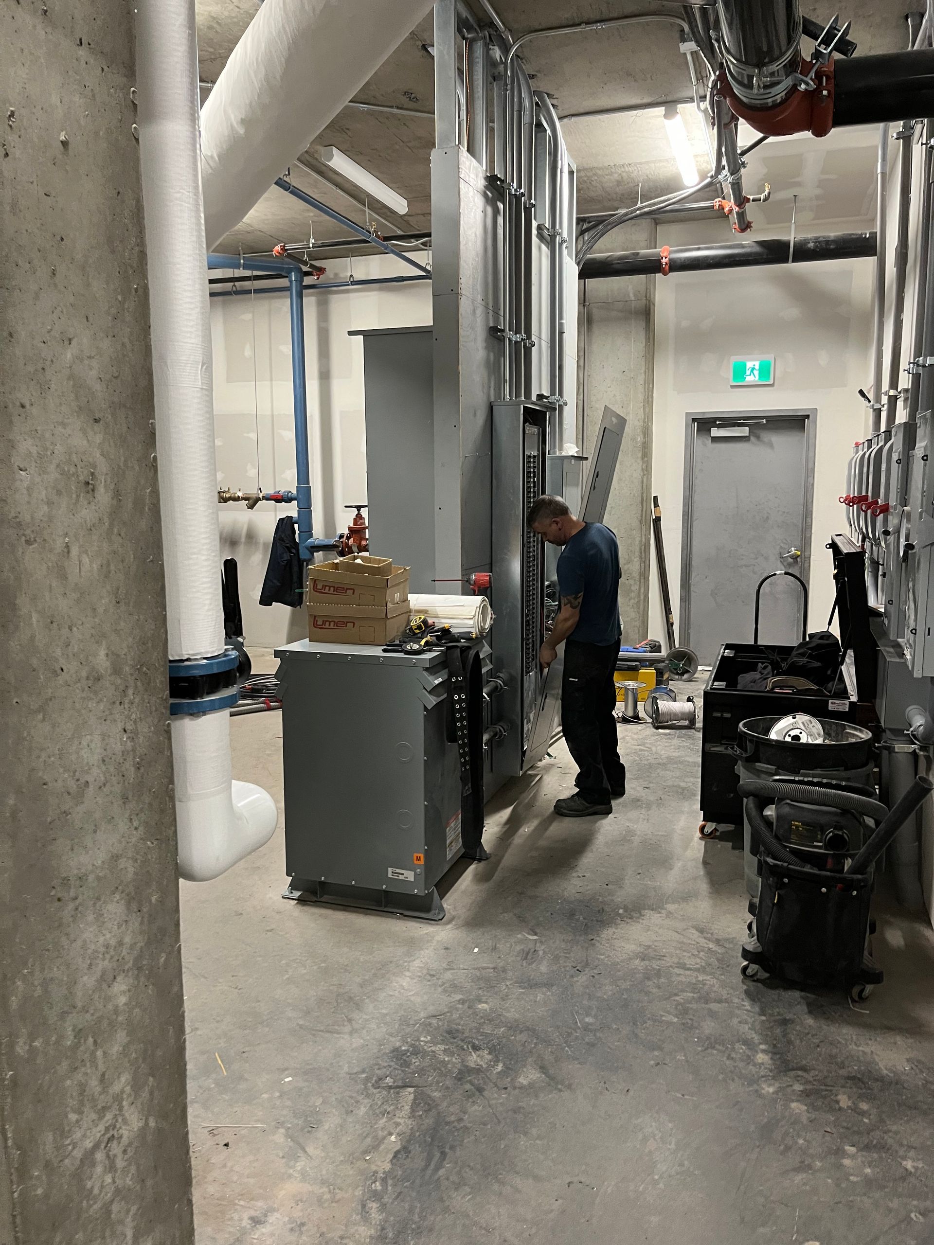 Un homme travaille sur une machine dans une pièce avec des tuyaux.