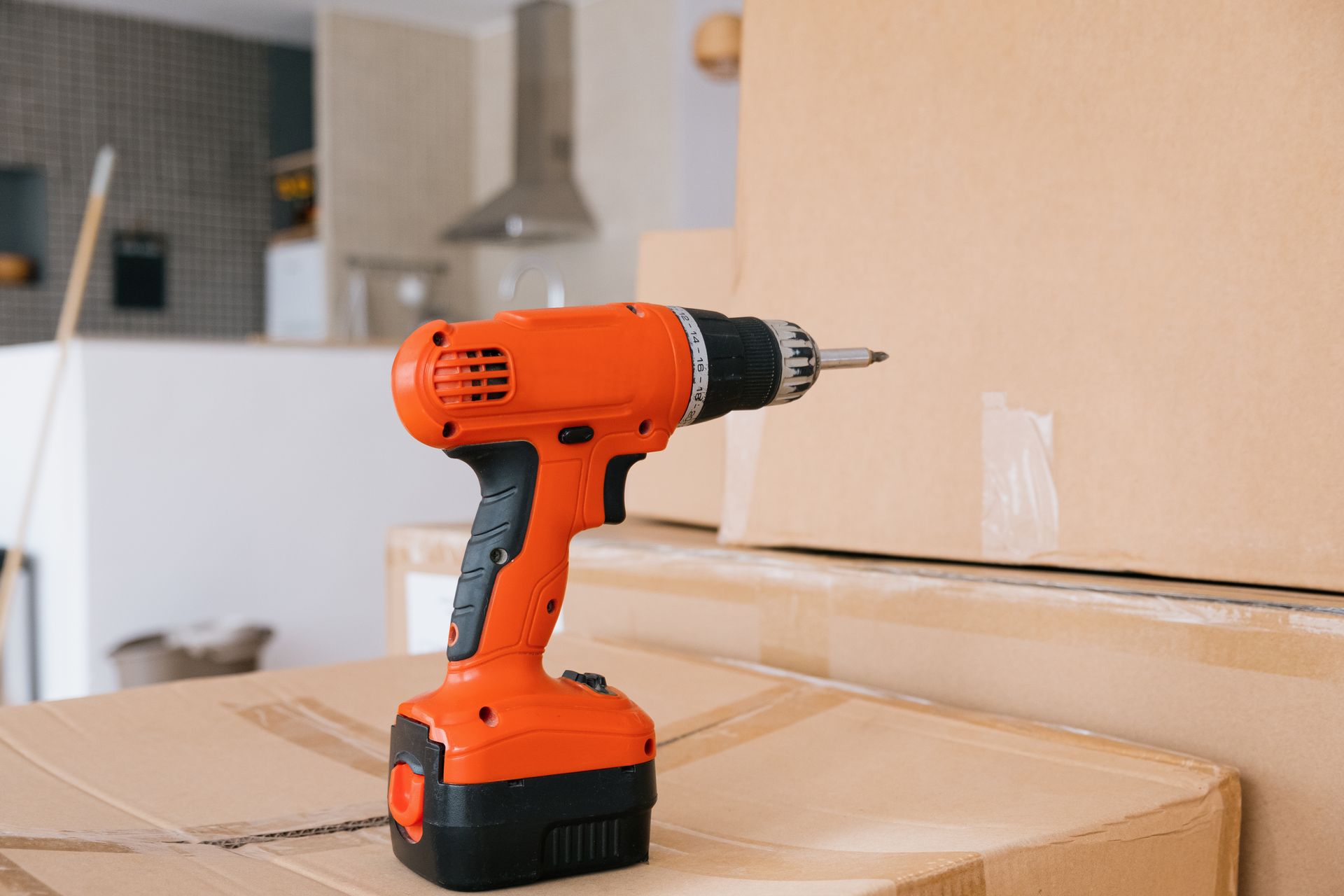 Orange cordless power drill on cardboard boxes during home renovation or moving. Orange cordless power drill on cardboard boxes during home renovation or moving.