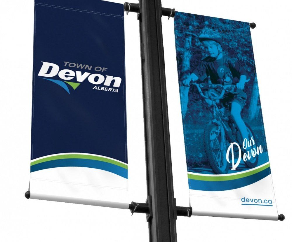 two banners for the town of devon are hanging on a pole .